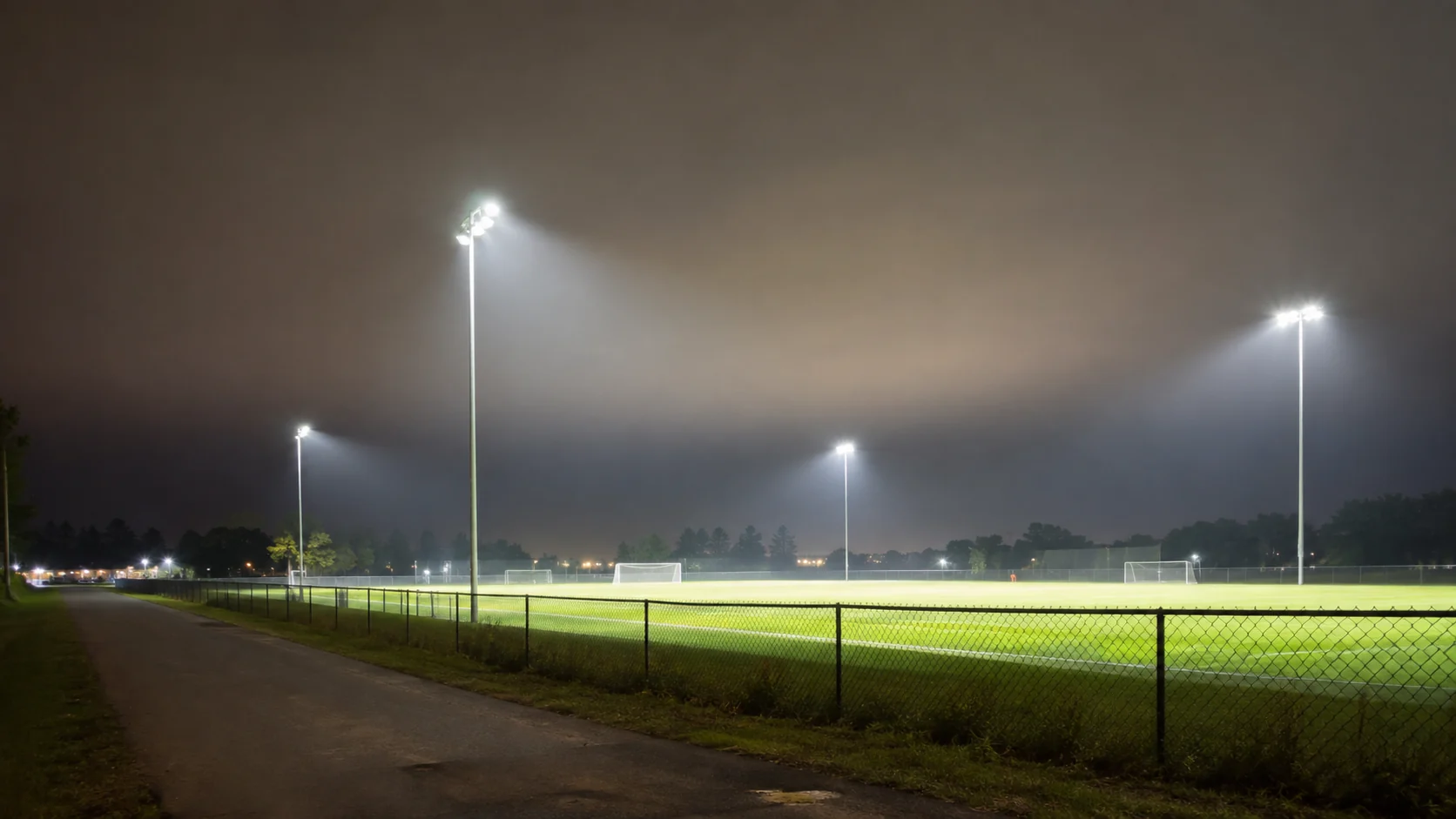Ground-level night view of a sports field with visible atmospheric haze above the illuminated playing area