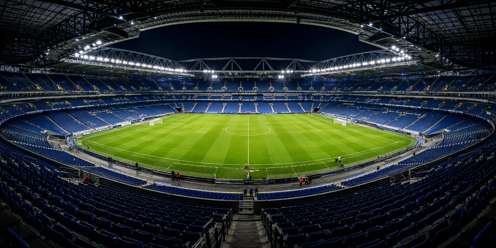 Real stadium interior showing illuminated turf, seating, roof structures and other surfaces that form the reflective context of a sports-lighting project